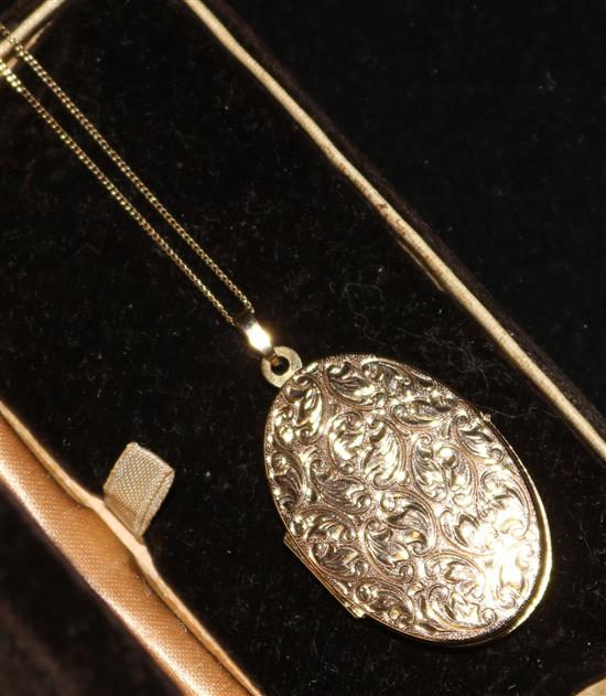 An engraved 9ct gold oval locket on a gold chain.